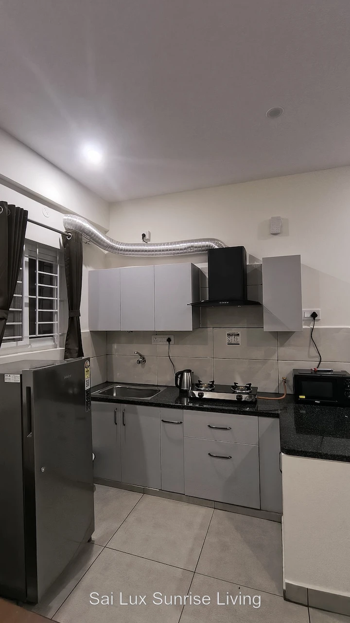 Dark modular kitchen with marble backsplash, copper chimney, gas hob, kettle, toaster and microwave
