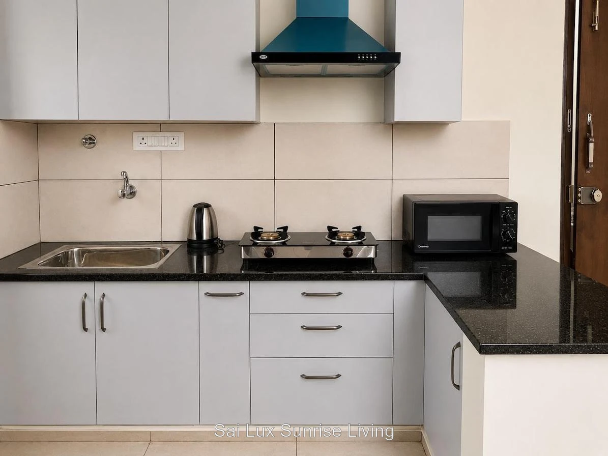 Premium modular kitchen with marble backsplash, brass fittings and induction hob at Sai Lux Sunrise Living